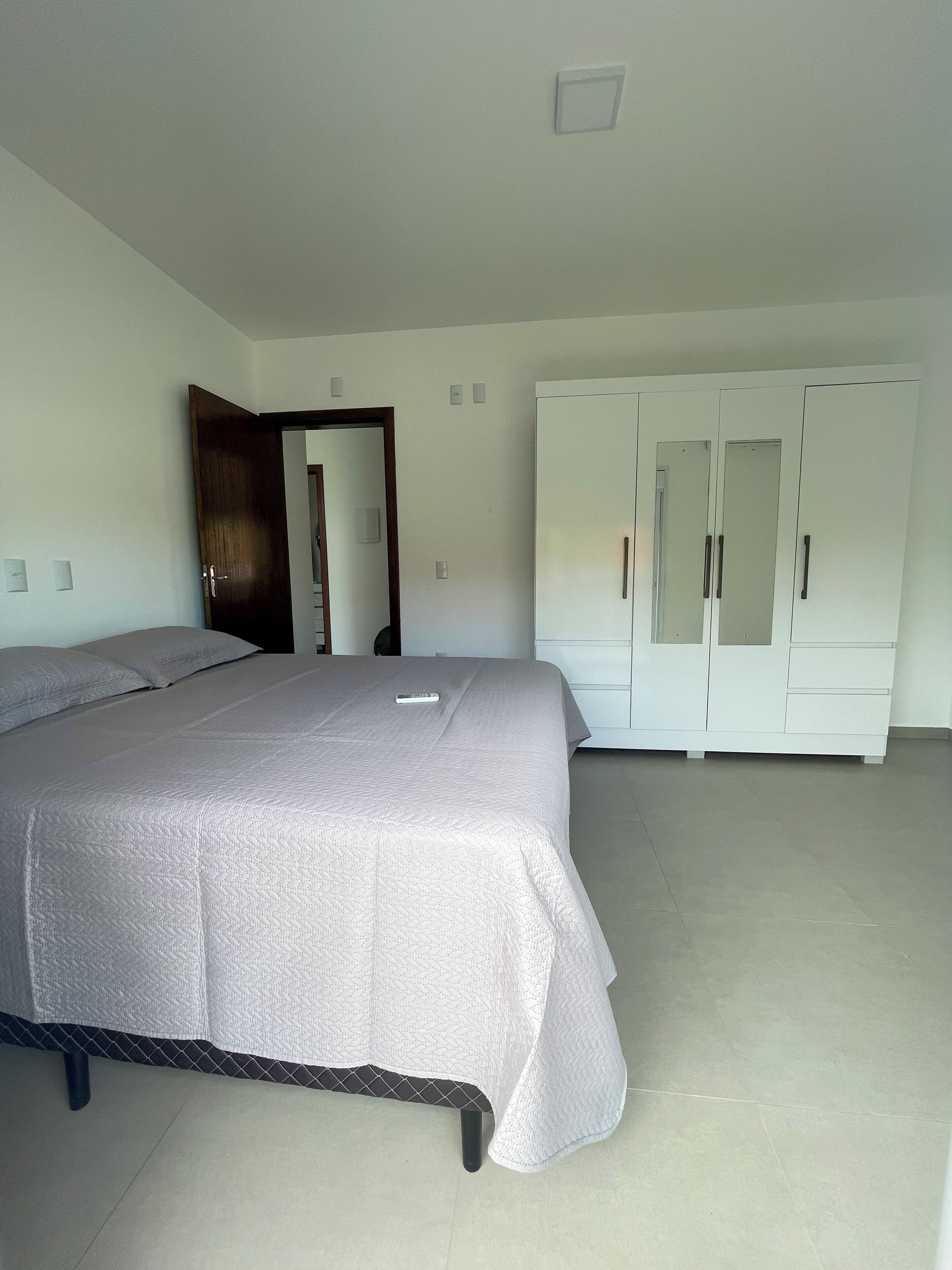 Quarto com cama, guarda-roupa e porta.
