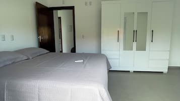 Quarto com cama, guarda-roupa e porta.