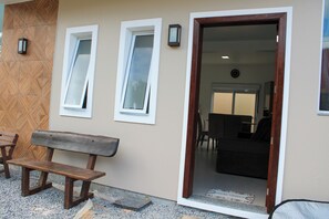 A room with a wooden bench, two windows, and a door leading to another space. - Azure Riviera Ferrugem (Garopaba)