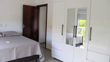 Um quarto com uma cama, um guarda-roupa e um espelho.