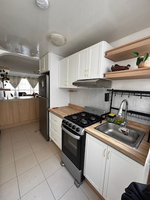 A kitchen with white cabinets, a stove, a refrigerator, and a sink. - Casa Josie - Queen Room, Upper Floor (Pachuca de Soto)