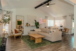A spacious living room with a high ceiling, a dining area, and a kitchen visible in the background. - Austin Home with Private Pool & Spa (Austin)