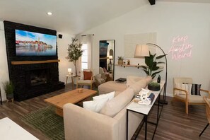 A living room with a fireplace, a television, and a neon sign. - Austin Home with Private Pool & Spa (Austin)