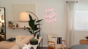 En moderne stue med sofa, stol, lampe og en neonskilte.