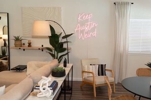 A modern living room with a sofa, a chair, a lamp, and a neon sign. - Austin Home with Private Pool & Spa (Austin)