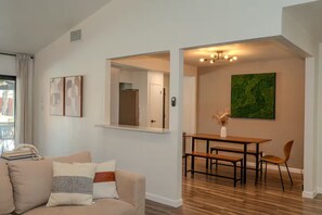 A modern living room with a sofa, a dining area with a table and chairs, and a green abstract painting on the wall. - Austin Home with Private Pool & Spa (Austin)