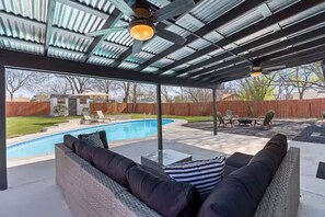 A covered outdoor area with a pool, seating, and a patio. - Austin Home with Private Pool & Spa (Austin)