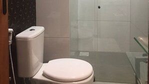 A bathroom with a toilet, a glass shower enclosure, and a patterned wall.