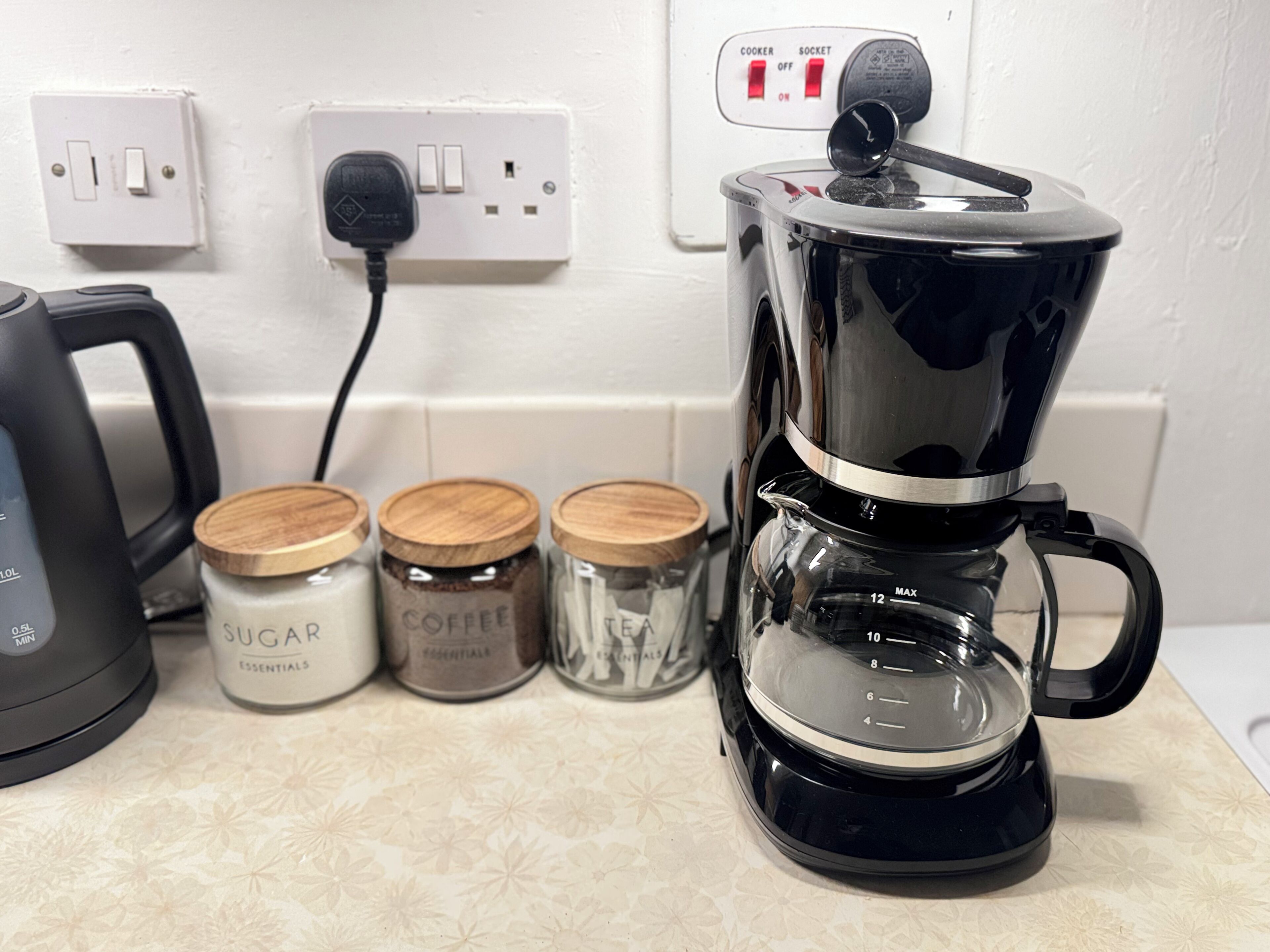 A kitchen counter with a coffee maker, sugar, and coffee containers.