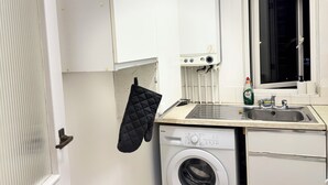 A compact kitchen with a washing machine, a sink, and a window. - Modern City Centre Apartment | Free Parking | Self Check-In (Southampton)