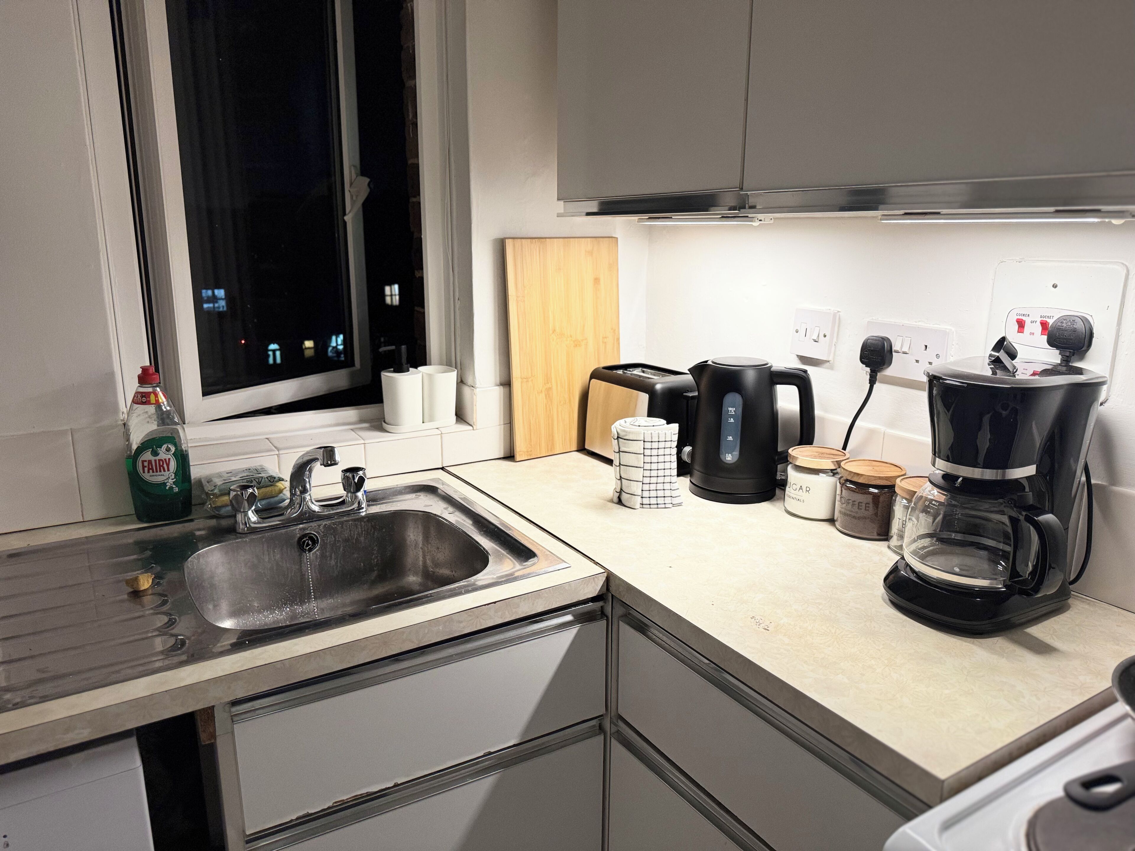 Eine Küche mit Spüle, Toaster, Wasserkocher, Kaffeemaschine und einem Fenster mit Blick nach draußen.