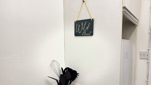 A kitchen area with a black sign saying 'Wild at heart' on the wall, a black utensil holder with a whisk, and two salt shakers labeled 'P' and 'S'. - Modern City Centre Apartment | Free Parking | Self Check-In (Southampton)