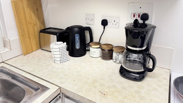 A kitchen with a coffee maker, a toaster, a kettle, and jars of sugar and coffee essentials. - Modern City Centre Apartment | Free Parking | Self Check-In (Southampton)