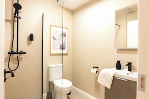 Un bagno con doccia, toilette, lavandino e un quadro appeso al muro.