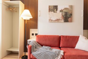 Una stanza con un divano rosso, una lampada da terra, una parete con listelli di legno e un quadro.