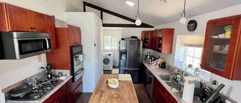 A modern kitchen with stainless steel appliances, wooden cabinets, and a central island.