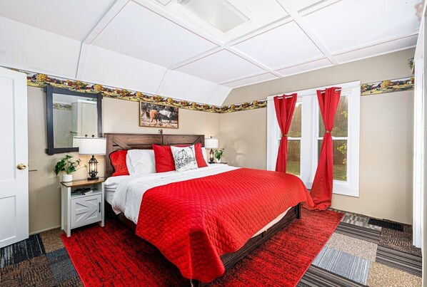 A hotel room with a bed, nightstands, a mirror, and a window with curtains.