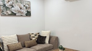 Ein modernes Wohnzimmer mit einem beigefarbenen Ecksofa, einem Holztisch und einem großen floralen Gemälde an der Wand.