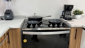Eine Küche mit einem schwarzen Herd, einer Kaffeemaschine und einem Mixer.
