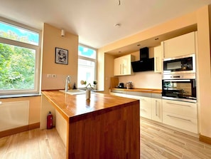 A modern kitchen with a central island, built-in appliances, and large windows. - Spacious 1 bedroom with 4 beds  (Luxembourg)