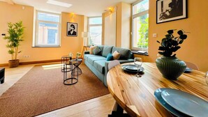 A modern living room with a sofa, a dining table, and a large window providing natural light. - Spacious 1 bedroom with 4 beds  (Luxembourg)