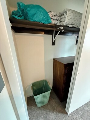 A storage area with a shelf, a green basket, and a wooden cabinet.