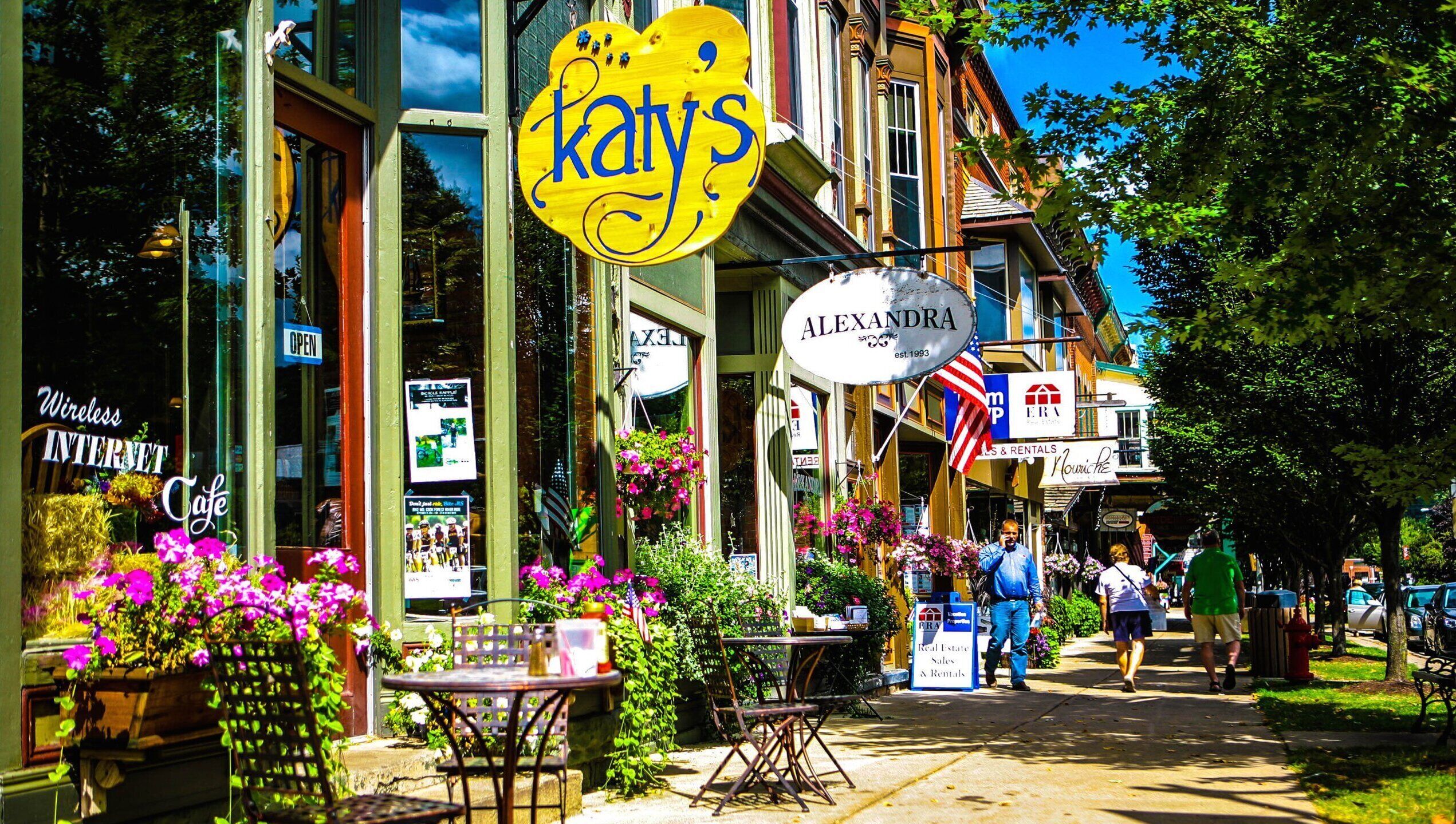 A cafe named 'Katy's' with outdoor seating and flower arrangements.