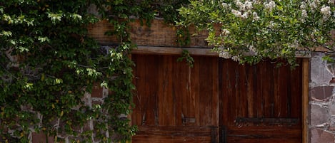 Una verja de madera con un muro de piedra y una planta en maceta al frente.
