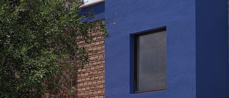 A modern building with a blue facade, a stone entrance, and a small window.
