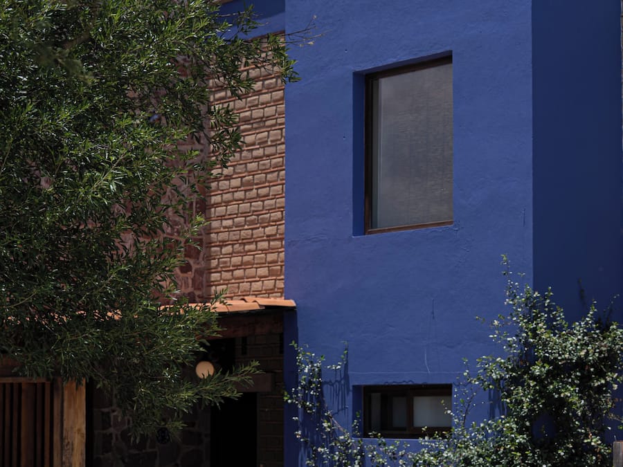 Un edificio moderno con fachada azul, entrada de piedra y una ventana pequeña.