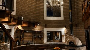 A rustic kitchen with exposed brick walls, a wooden ceiling, and a brick oven. - Viñedo Luka XVXV (San Miguel de Allende)