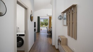 Un corridoio con una lavatrice, una sala da pranzo con tavolo e sedie, e vista all'esterno.