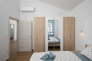 A bedroom with a bed, a wardrobe, and a bathroom visible through a mirrored closet door. - Villa Martha with Private Pool and Olive Garden near Pula (Šišan)