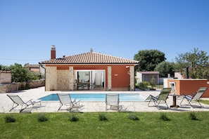 Une maison avec une piscine, un espace extérieur aménagé et un mur en pierre.