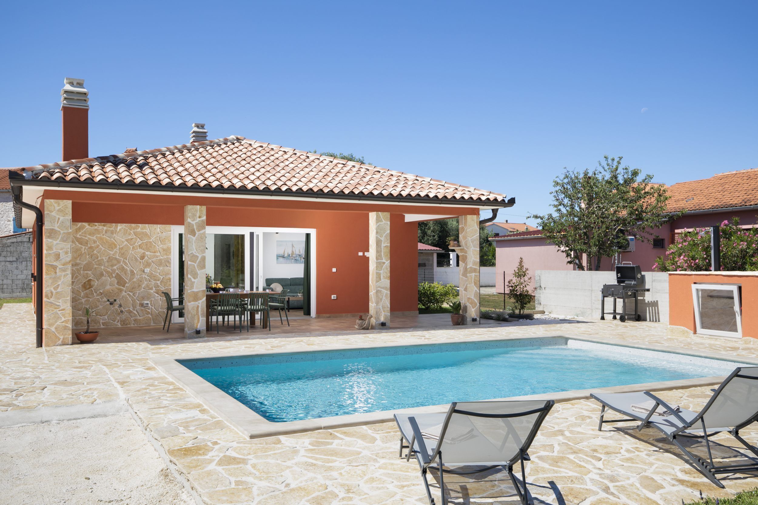 A house with a swimming pool, outdoor seating, and a patio area.