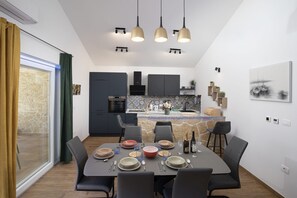 Uma cozinha moderna com armários escuros, uma ilha central e iluminação pendente.