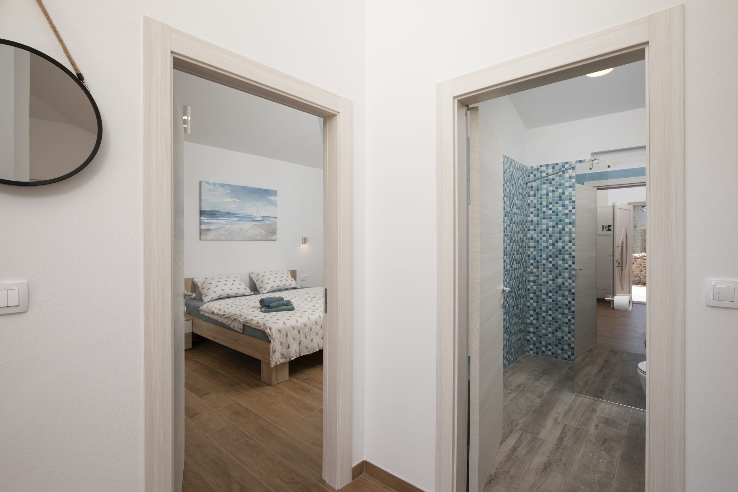 Un dormitorio con una cama, una mesita de noche, una lámpara de pared y un cuadro.