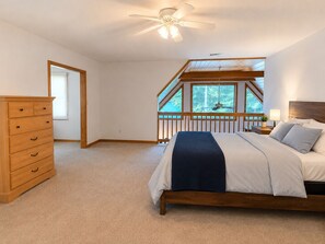 Un dormitorio con cama, cómoda, ventilador de techo y ventana con vistas.