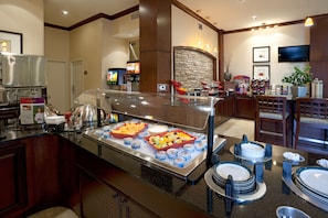 A buffet area with a variety of food items, a coffee station, and a seating area with tables and chairs.