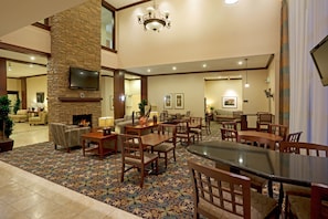 A spacious lobby with a fireplace, comfortable seating, and a large dining area.