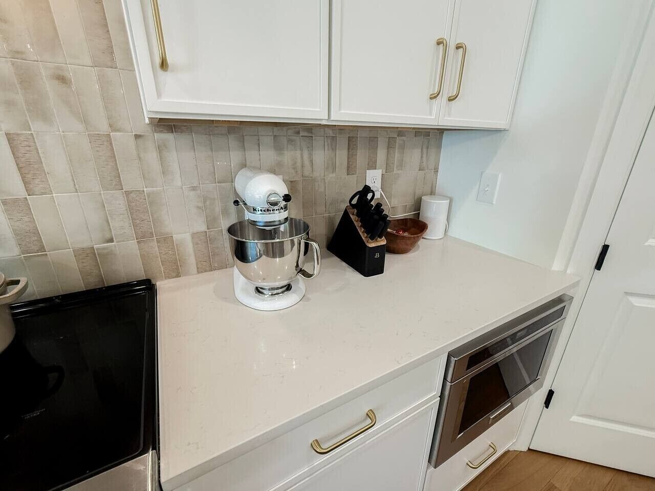 A kitchen with white cabinets, a coffee maker, a kettle, and a microwave.