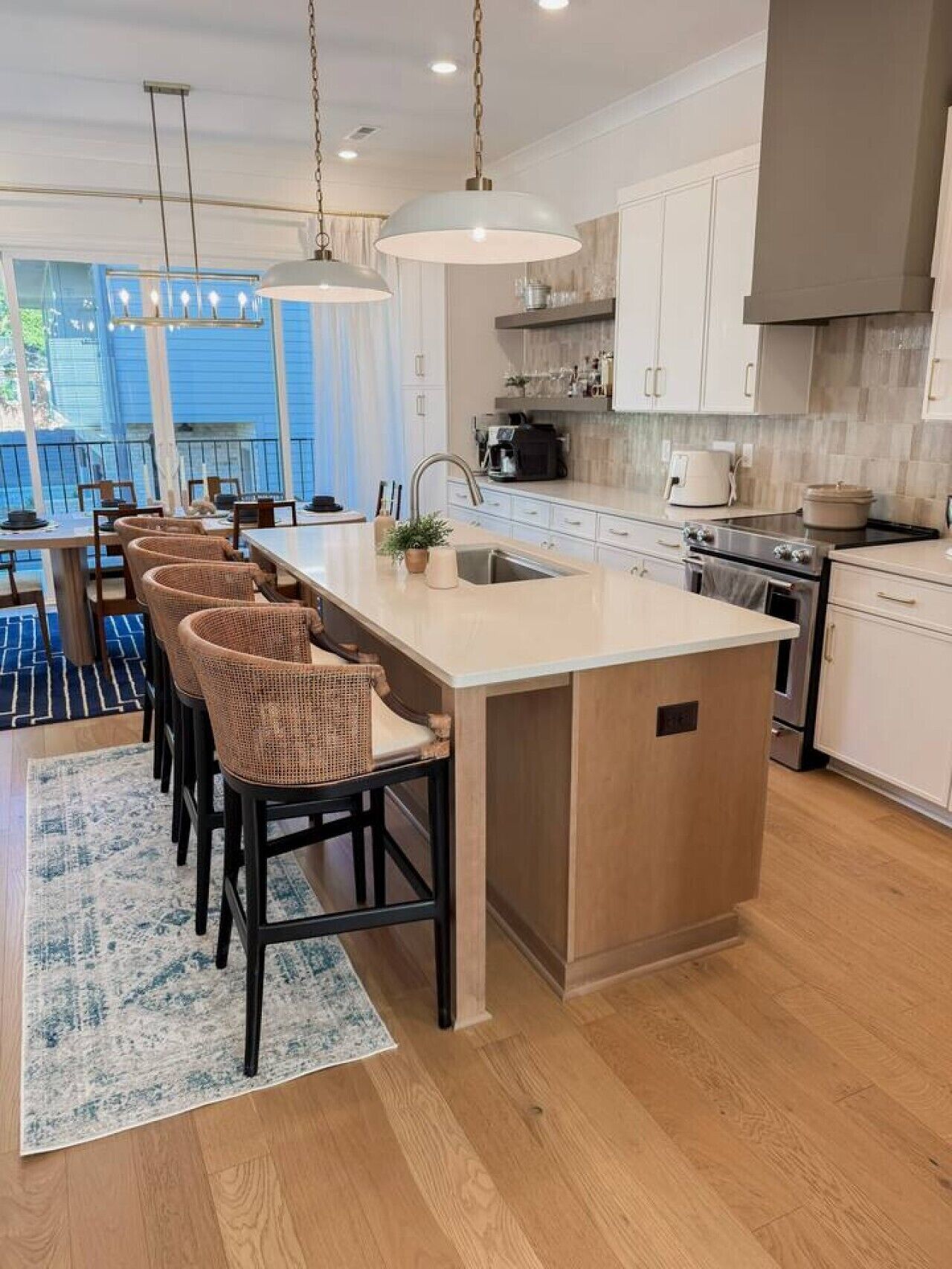 A modern kitchen with a central island, bar stools, and pendant lighting.