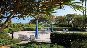 En strand med hængekøje, liggestole og volleyballnet.