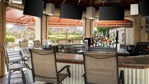 Eine Bar mit Theke, Stühlen und Blick auf einen Garten.
