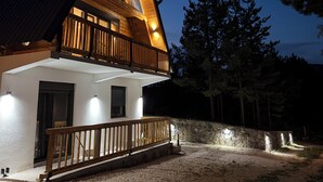 Ein zweigeschossiges Holzhaus mit Balkon, Steinmauer und Kiesweg.