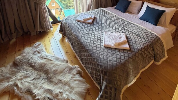 Ein Schlafzimmer mit einem Bett, Kissen, einem Fellteppich und Vorhängen.