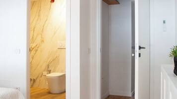 Un baño moderno con pared de mármol, suelo de madera y inodoro blanco.