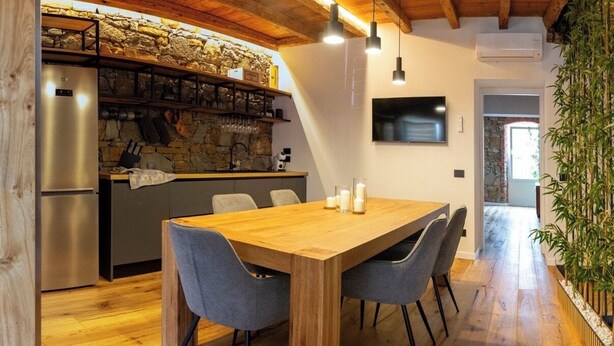 Una cucina moderna con parete in pietra, frigorifero integrato e tavolo da pranzo in legno con sedie.