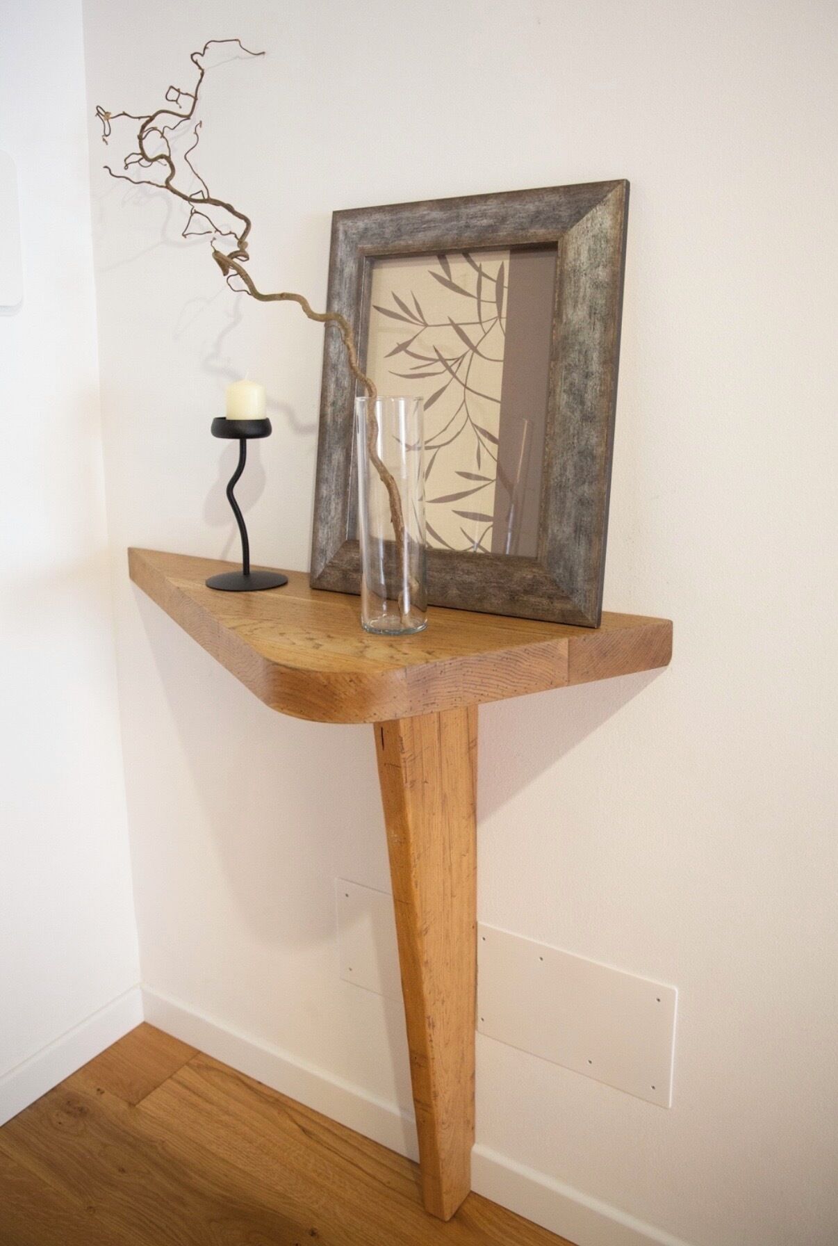 A wooden console table with a mirror, a candle holder, and a glass vase.