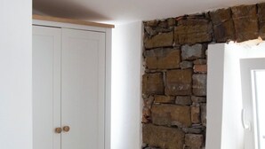 Una stanza con un armadio bianco, un muro in pietra e un pavimento in legno.